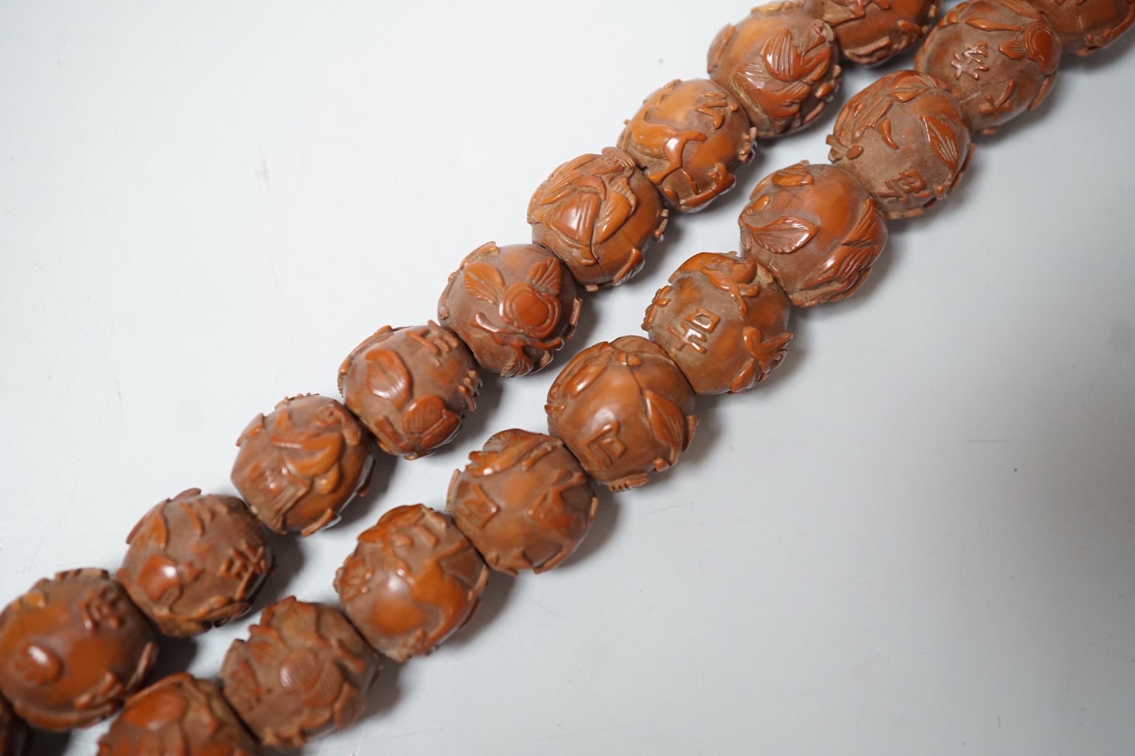 A Chinese necklace of 94 carved coquilla nuts/peach stones